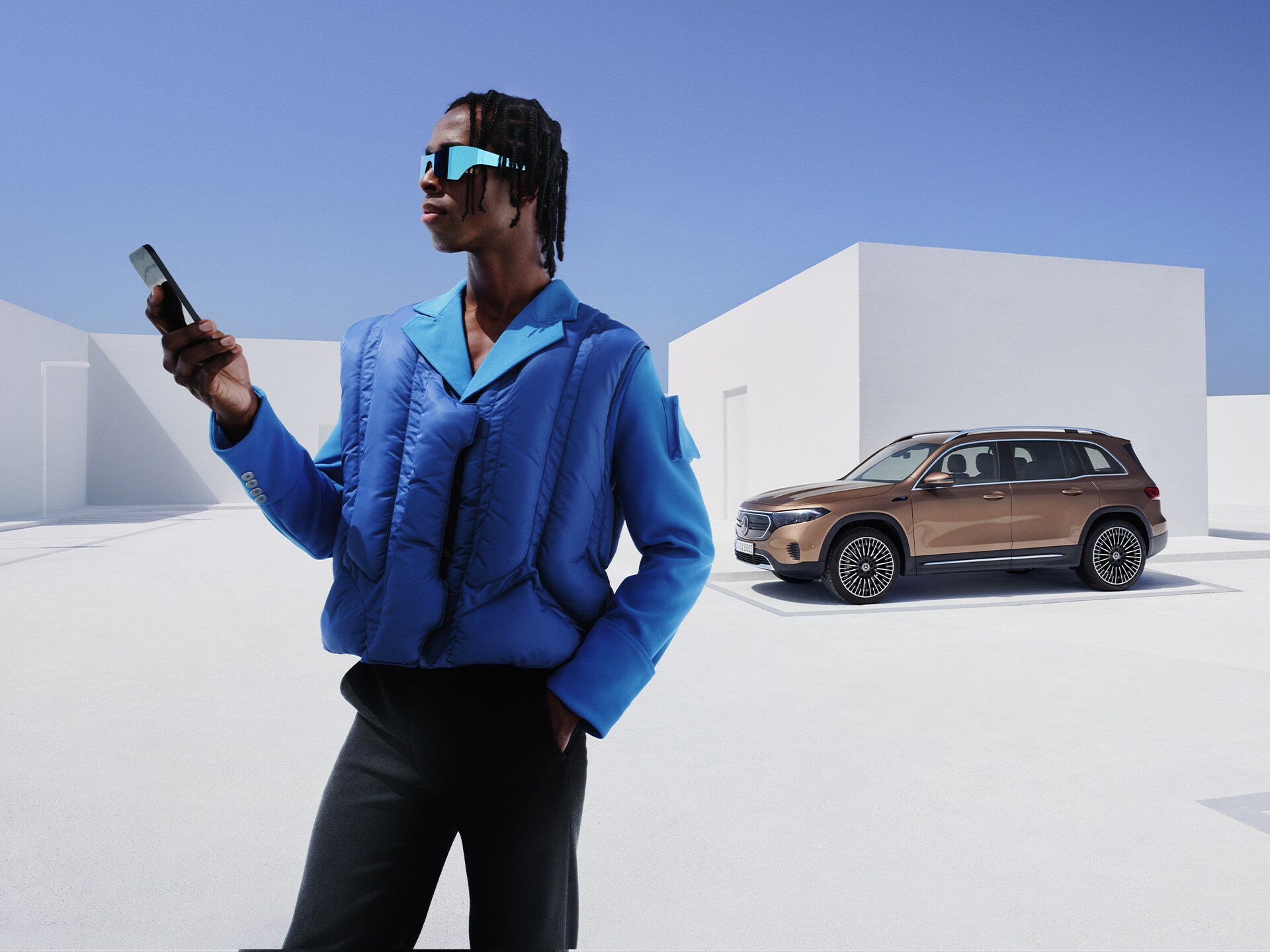Mercedes-Benz App | Applicazioni | Mercedes-Benz Una persona con uno smartphone in mano e una auto sullo sfondo