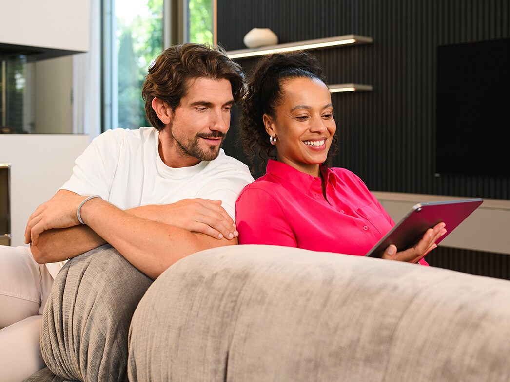 FInance | Mercedes-Benz Due persone su un divano che guardano un dispositivo mobile.